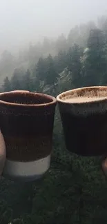 Hands holding coffee mugs in a misty forest, perfect for nature lovers.