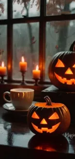 Halloween pumpkins and candles by a window create a cozy, festive ambiance.