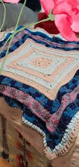 Colorful crochet blanket with pink accent.