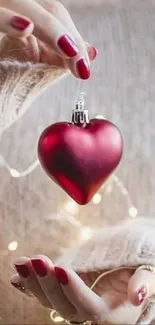 A red heart ornament held by hands with fairy lights.