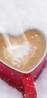 Heart-shaped coffee in a red mug with steam on a white snowy background.