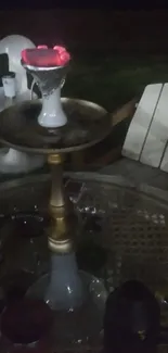 Hookah glowing warmly on outdoor table at night.