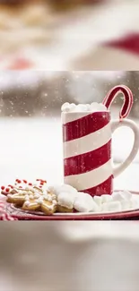 Candy cane mug with hot chocolate and cookies surrounded by snow. Cozy holiday theme.