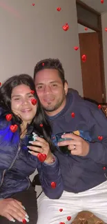 Couple enjoying a cozy moment indoors, smiling with drinks.