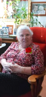 Woman in a cozy chair with red and floral decorations.