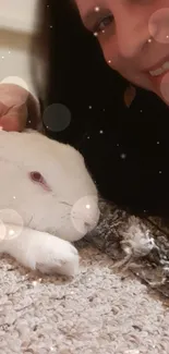 Person cuddling with a fluffy white bunny on a soft textured surface.