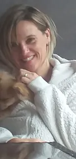 Woman smiling while holding a small dog.