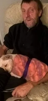 Man relaxing with a dog sleeping on his lap in a cozy setting.