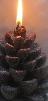 Pinecone candle glowing with warm light.