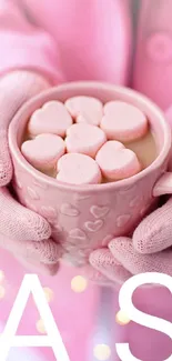 Pink mug with heart marshmallows on cozy background.