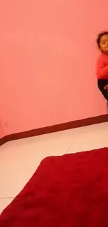 Child in a cozy pink room with a red carpet.