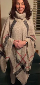 Woman wears a cozy plaid poncho in a home setting.