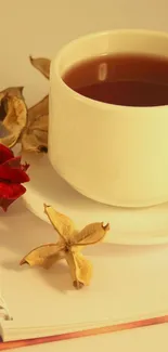 Cozy wallpaper with tea cup, dried leaves, and notebook in warm tones.