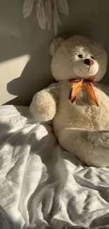 Cozy teddy bear with orange bow on a sunlit bed.