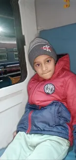 Child in cozy attire during a train journey.