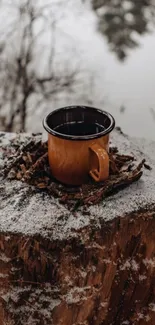 Rustic brown mug on snowy tree stump in winter scene.