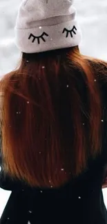 Girl with long hair in a snowy background, wearing a cute winter beanie.