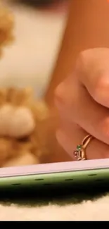 A close-up of a hand writing with a ring, next to a fluffy teddy bear.