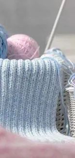 Soft pastel knitting theme with yarn balls in light blue and pink hues.