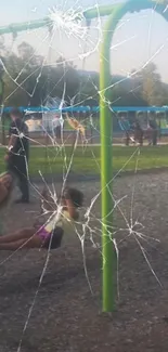 Swing set in park with cracked screen effect overlay.