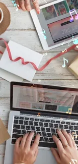 Creative workspace with laptop, tablet, and artistic supplies on wooden table.