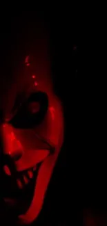 Creepy clown face in dark red lighting.