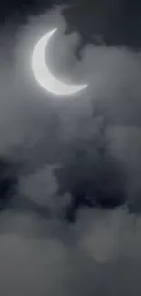 Crescent moon amidst gray clouds at night.