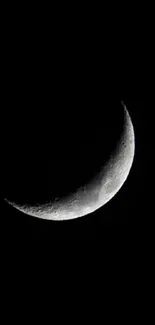 Crescent moon shining in the dark night sky against a black background.