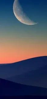 Crescent moon over a twilight sky with dark silhouetted hills.