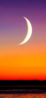 Crescent moon over vibrant sunset sky, with striking orange and purple hues.