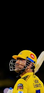 Cricketer wearing a yellow jersey and helmet holding a bat.