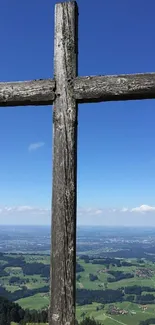 Rustic cross overlooking scenic mountain view on a clear day.