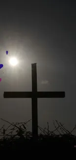 Silhouette of a cross with sunlight and hearts.