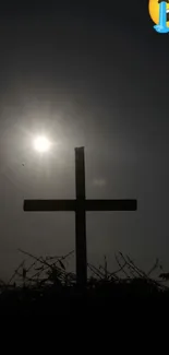 Silhouette of a cross in front of the sun with a crying emoji above.