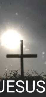 Silhouette of cross with sun shining behind in dramatic setting.