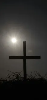 Silhouette of a cross with bright sun in the background.