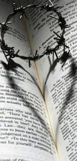 Barbed wire crown casting heart shadow on Bible pages.