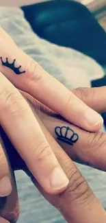 Two hands with crown tattoos, symbolizing love.