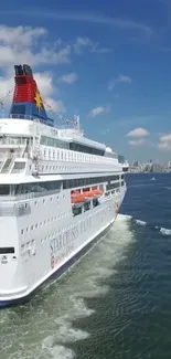 A cruise ship sails under a sunny blue sky.