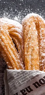 Churros covered in sugar on a dark background with scattered powdered sugar.