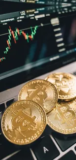 Bitcoin coins on a laptop with a trading graph screen.