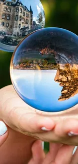 Crystal balls reflecting castle and nature, held in hands.