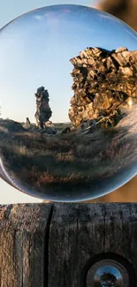 Crystal ball reflecting rocky landscape on a wooden post.