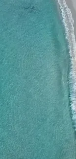 Aerial view of serene blue ocean waves on sandy beach.