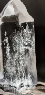 Close-up of a clear quartz crystal with dark background for mobile wallpaper.