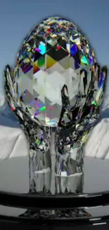 Crystal egg held by glass hands with snowy mountain background.