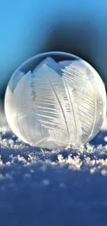 Frosty crystal ball on snowy surface with bright blue sky.