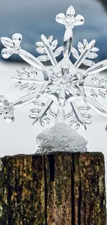 Clear crystal snowflake on rustic wood post with winter background.