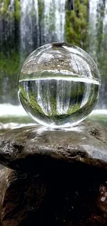 Crystal sphere reflecting waterfall scene on rocks.