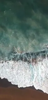 Aerial view of ocean waves crashing on sandy beach.